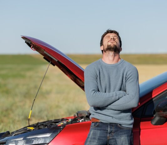 Vodič umiestňuje výstražný trojuholník za pokazené auto na diaľnici.