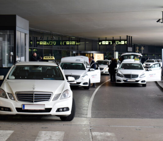 Cestujúci s kufrom nastupuje do taxi pred letiskom Schwechat.